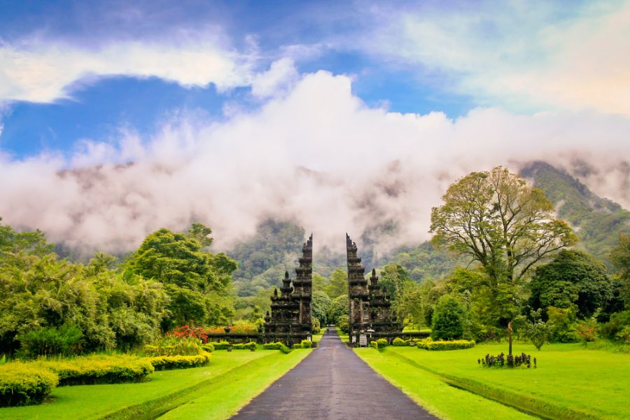 Bali luxury travel temple gate with rolling clouds and emerald hills